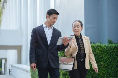 İş ortağı olan kıdemli kadın yatırımcı modern şehirde duruyor ve birlikte yeni proje gelişimini tartışıyorlar..