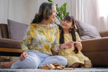 Mutlu yetişkin büyükanne evde küçük anaokulu torunuyla oynarken eğleniyor..