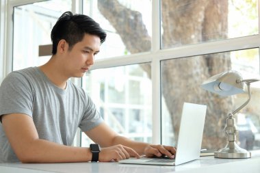 Parlak ofiste bilgisayarla çalışan yakışıklı iş adamı..