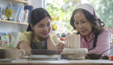 Genç zanaatkar, olgun bir kadının çömlek atölyesinde seramik demlik yapmasına yardım ediyor. Yaratıcı aktiviteler, seramik sanat konsepti..