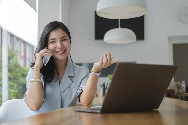 オフィスに座っている間に携帯電話で話しているビジネスマンの女性 — ストック写真