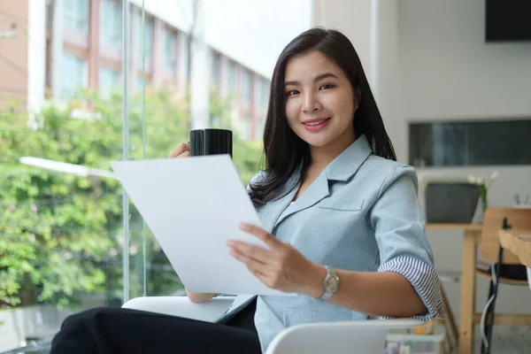 輝くアジアの実業家が明るい現代オフィスに座ってドキュメントを読む — ストック写真