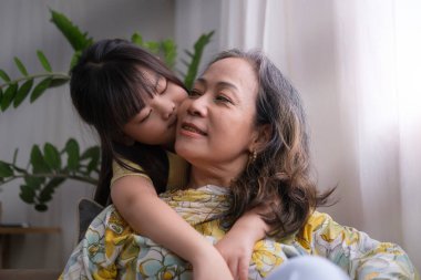 Okul öncesi torun kızı büyükannesini yanağından öpüyor. Aile hayatı kavramında sevgi ve farklılıkların nesli..