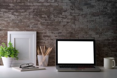 Laptop computer, picture frame, houseplant and stationery on white table. Modern workplace.	