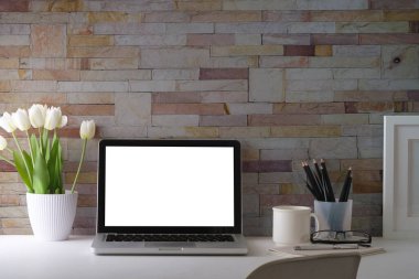 Bilgisayarı, saksısı, kahve fincanı, çerçevesi ve kırtasiyesi olan ofis masası..