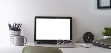 Laptop bilgisayarı, kahve fincanı, kırtasiye malzemesi ve ev bitkisi olan ofis masası. Reklam metniniz için boş ekran.