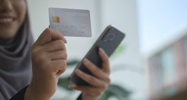 Kredi kartı ve akıllı telefon taşıyan müslüman bir kadının internet üzerinden alışveriş yapması ya da internetten alışveriş yapması..