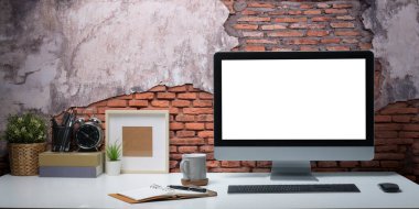 Bilgisayarı, kahve fincanı, kalem tutacağı ve beyaz masasında bitkisi olan yaratıcı iş yeri.