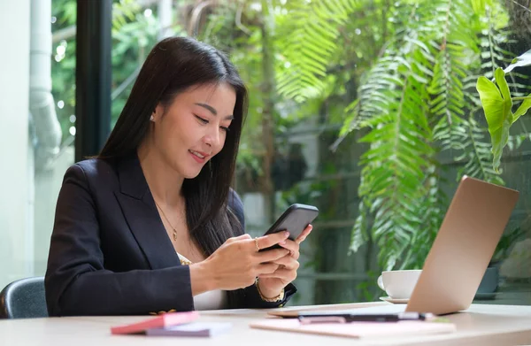 坐在办公室里用智能手机的年轻亚洲女人 — 图库照片