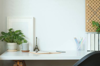 Boş çerçeve, kahve fincanı, kitaplar ve bitki yetiştirme saatleriyle rahat bir iş yeri..