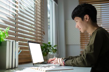 Focused young asian man working online, reading business email on laptop computer.