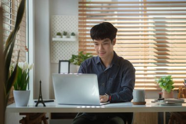 Asian man freelancer working online with computer tablet at home.	