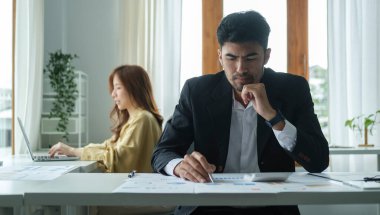 Ofisteki mali verileri analiz etmek için hesap makinesi kullanan konsantre bir işadamı..