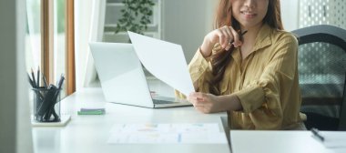 Dizüstü bilgisayar kullanan ve iş yerinde finansal istatistik grafikleriyle çalışan kadın ekonomist.