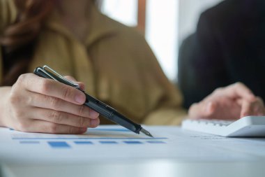 Hesap makinesi kullanan ve mali grafiği analiz eden ya da istatistik ve tahminleri kontrol eden profesyonel iş kadını.