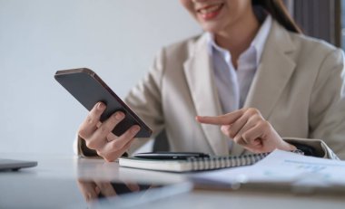 Gülümseyen kadın çalışan sosyal medyayı kontrol ediyor, akıllı telefondan sohbet ediyor..