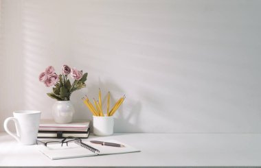 Kahve fincanı, saksı, kahve fincanı, kitap ve bardaklar beyaz masada..