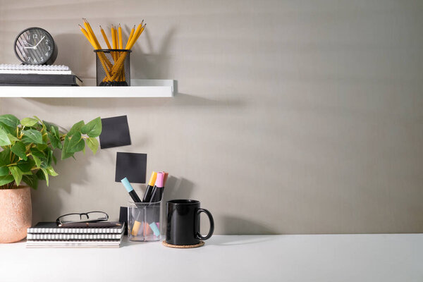 Creative workplace with supplies, house plant and coffee cup on white table. Copy space for your advertise text.