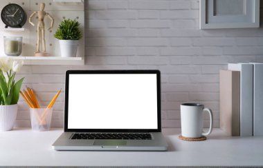 Contemporary workplace with laptop computer, picture frame, stationery and flower pot. Blank screen for your advertise text.