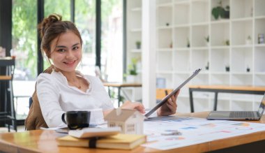 Attractive young female investor using laptop and working with financial documents.