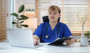 Doctor with with stethoscope using laptop at his workplace. Healthcare, medical and technology concept.