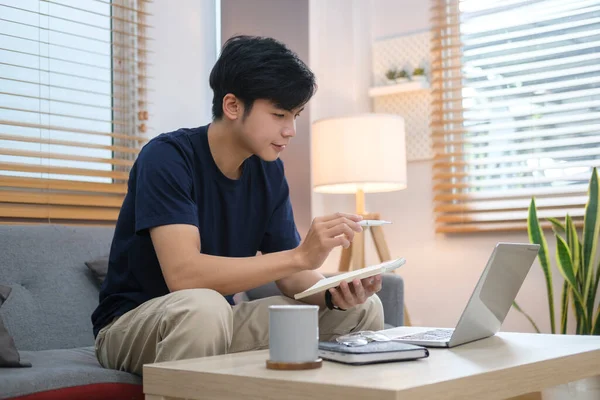 Молодий Азіатський Чоловік Працює Дому Використовуючи Ноутбук Дивані Світлій Вітальні — стокове фото