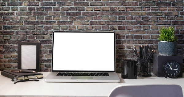 Computer laptop with empty screen, coffee cup, potted plant and stationery on white table.