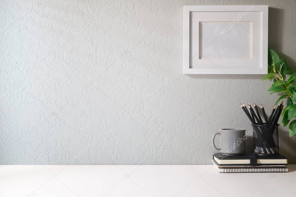 Blank picture frame, coffee cup, notebook and house plant. Home office desk, Copy space for your text.