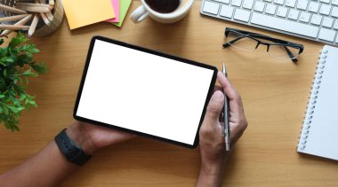 Ahşap ofis masasında dijital tablet kullanan işadamlarının genel görünümü.