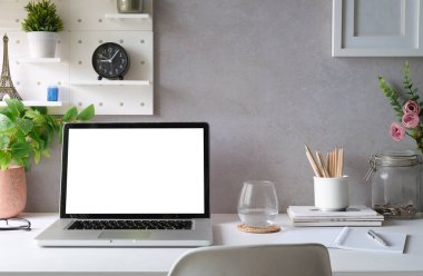 Front view laptop, coffee cup houseplant and stationery on white table. Empty screen for your advertise text.