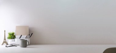 Minimal workplace with coffee cup pencil holder notebook and flower pot on white table. Copy space for your advertise text.