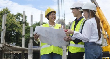 Engineer team in protective helmets and vests inspecting construction site. Engineering and architecture concept. 
