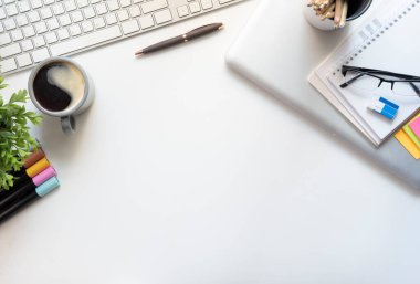 White office desk with notepad, sticky notes, glasses and coffee cup. Top view with copy space.	