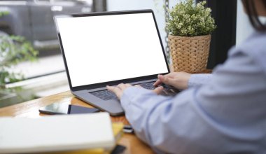 Over shoulder view of businesswoman  using laptop computer while sitting near window at coffee shop.