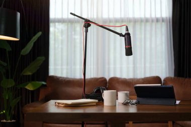 Sound recording and broadcasting equipment with microphone, laptop and headphones on wooden table in the home studio. Podcasting, broadcasting concept.