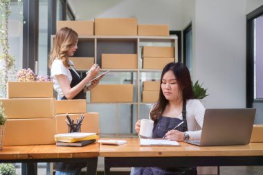 Partnership of small business entrepreneur working together at  warehouse, preparing parcel boxes of product for delivery to customer.
