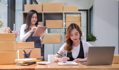 Two startup small business entrepreneurs are working, preparing parcel boxes of product for delivery to customer.	