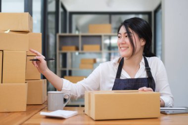 Young woman startup small business entrepreneur preparing parcel boxes of product for deliver to customer.	