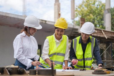 Engineers in yellow vests and safety helmet working at construction site. Building construction collaboration concept.
