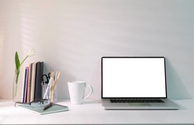 Bright modern home office with laptop, supplies and flower pot on white table. Empty screen for your advertise text.	