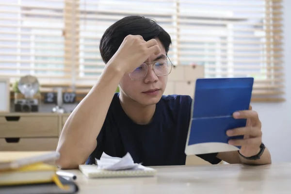 Worried asian man calculating bills, upset about money problem, manage household finances at home.