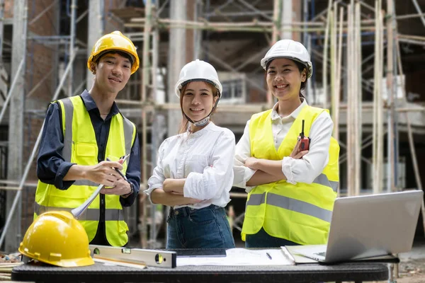 Group of architect and engineers wearing safety helmet and vast standing with arms crossed and looking to camera. Industry, Engineer, construction concept.