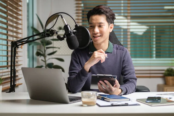 Handsome man radio host streaming podcast with microphone while streaming live audio podcast in home studio.
