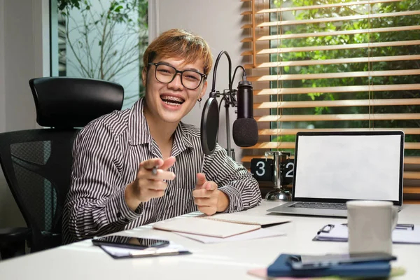 Young man radio host streaming podcast with microphone while streaming live audio podcast in home studio.