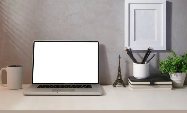 Front view laptop, coffee cup houseplant and stationery on white table. Empty screen for your advertise text.