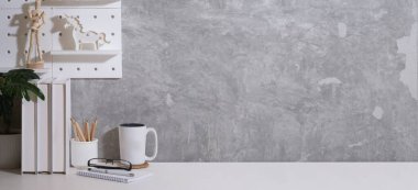 Kitapları, kahve fincanı, saksısı ve kalem tutacağı olan çağdaş bir iş yeri. Metnin için boşluk kopyala.