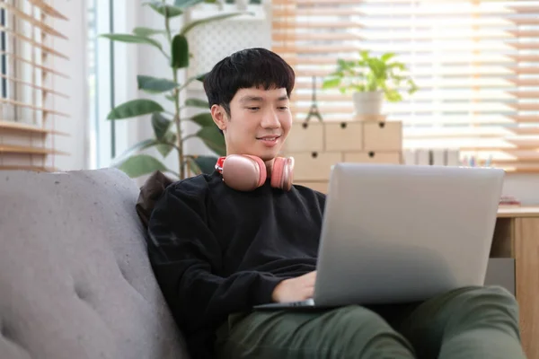 Young Asian Man Working Home Using Laptop Couch Bright Living — Stock Photo, Image