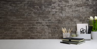 Tuğla duvara karşı çiçek saksısı, kitap ve kırtasiyeli hippi işyeri.