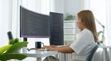 Modern ofiste yeni bir proje üzerinde çalışırken bilgisayar üzerinde çalışan odaklanmış kadın programcı.