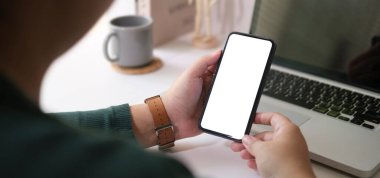 View over shoulder of woman hands holding smart phone. Empty screen for your advertise text.	